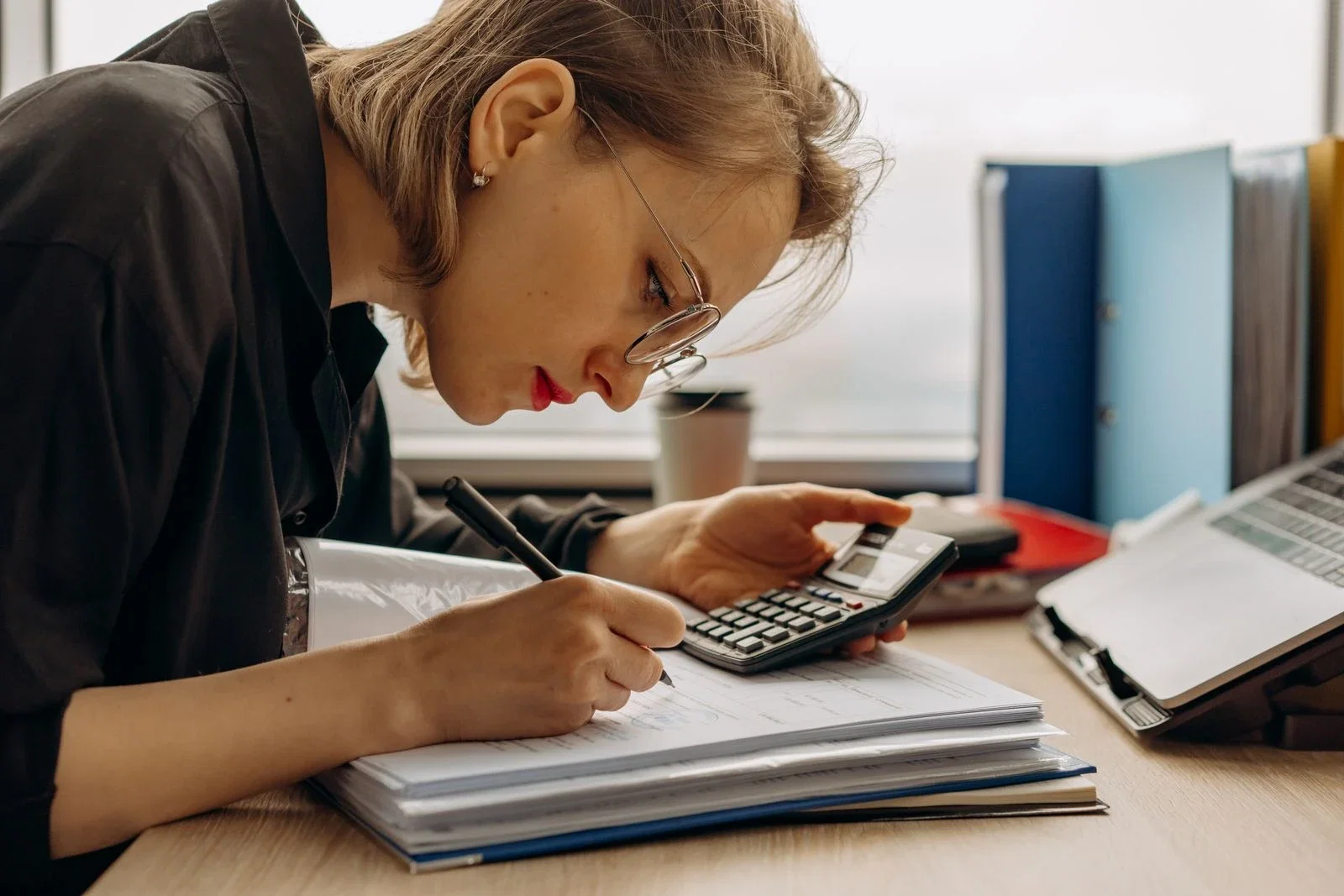 Bookkeeper focused on calculations with documents at a desk