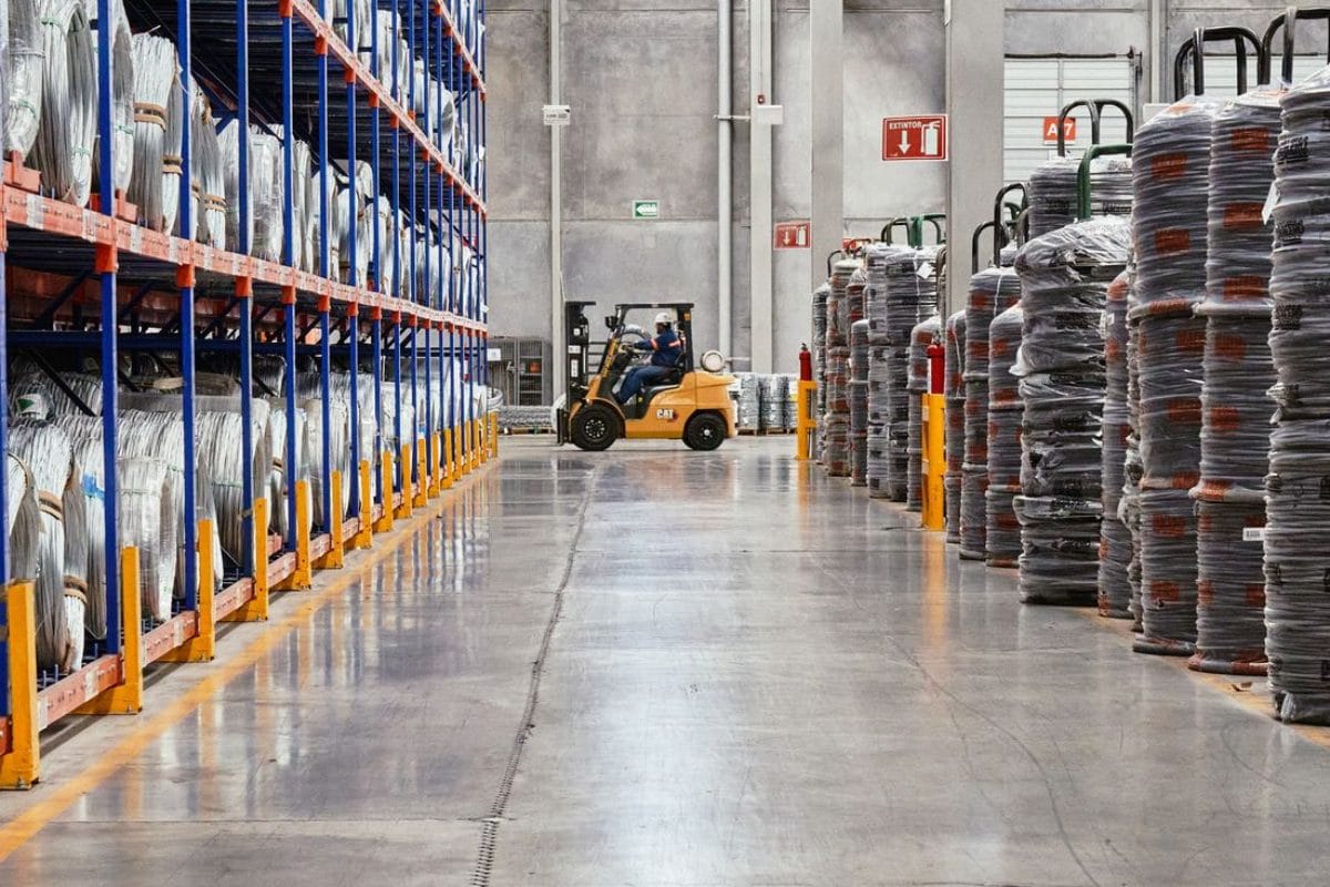 Forklift moving coiled raw material stock through the goods-in racking aisle